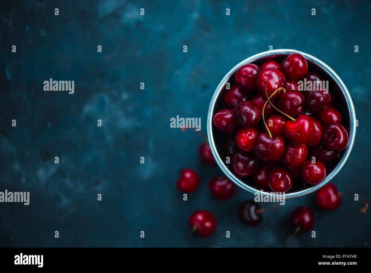 Cherries with a small metal bucket on a grey concrete background, summer berries concept with copy space. Neutral color tones still life Stock Photo