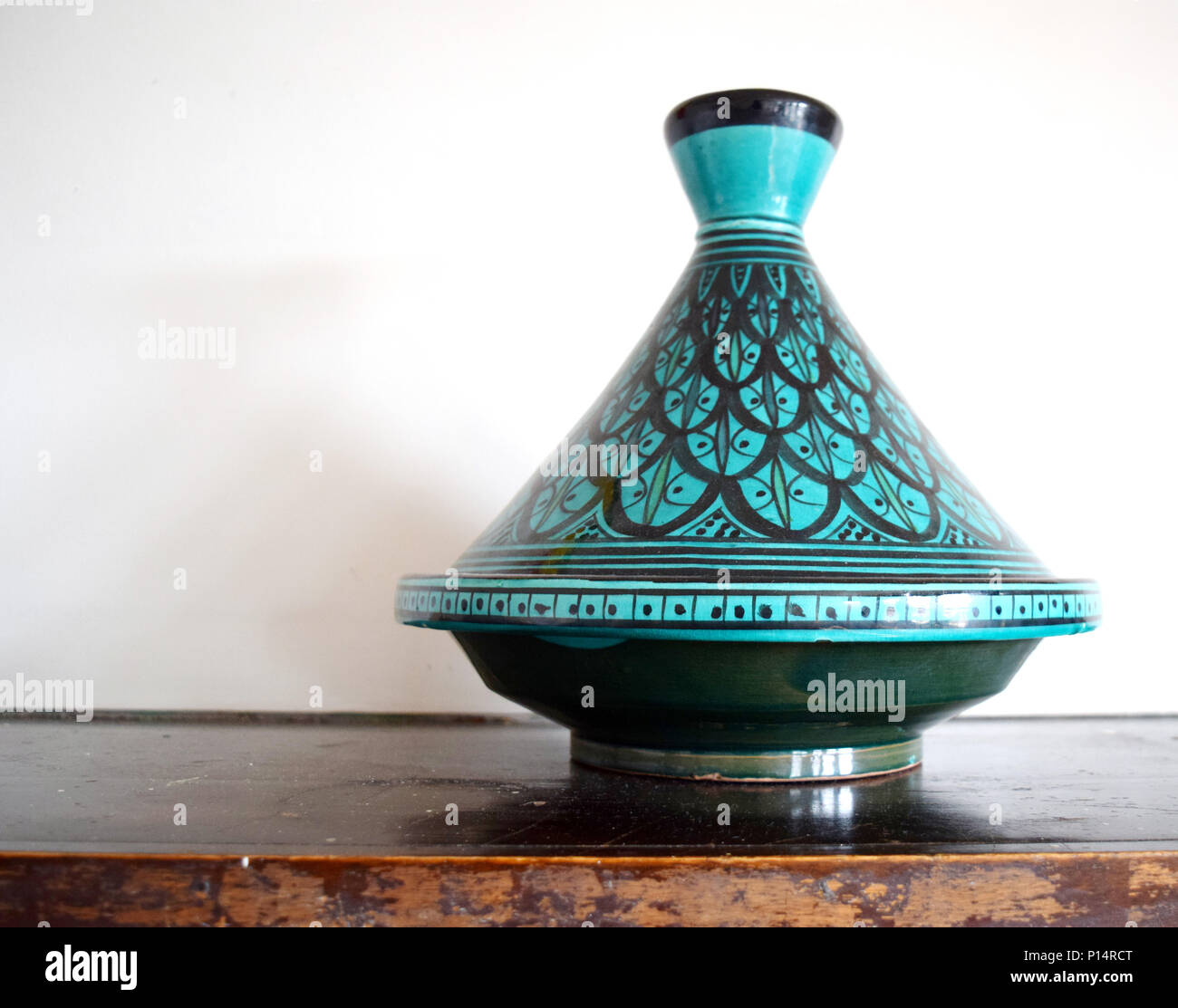 Green and black Moroccan tagine (cooking vessel) on a table Stock Photo
