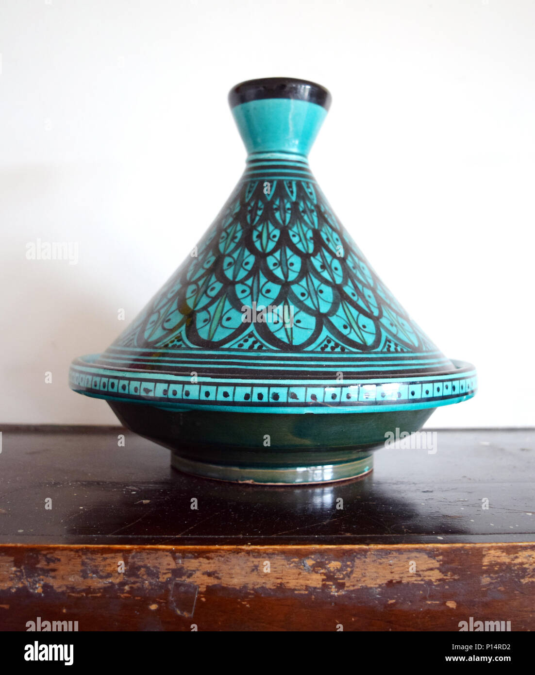 Green and black Moroccan tagine (cooking vessel) on a table Stock Photo