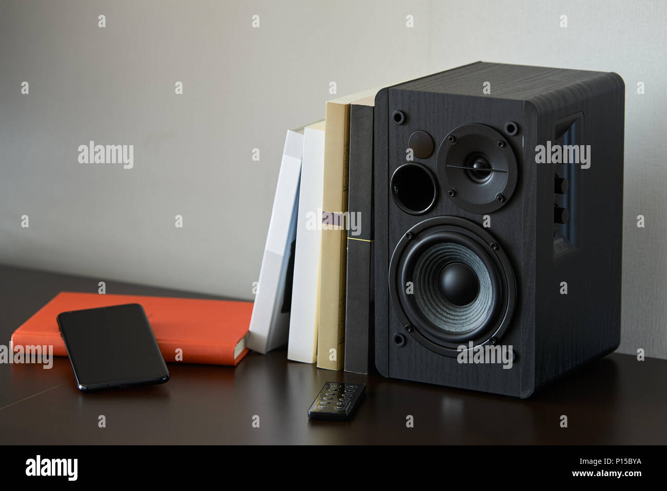 bookshelf speaker with books, smartphone and remote controller on a TV stand Stock Photo Alamy