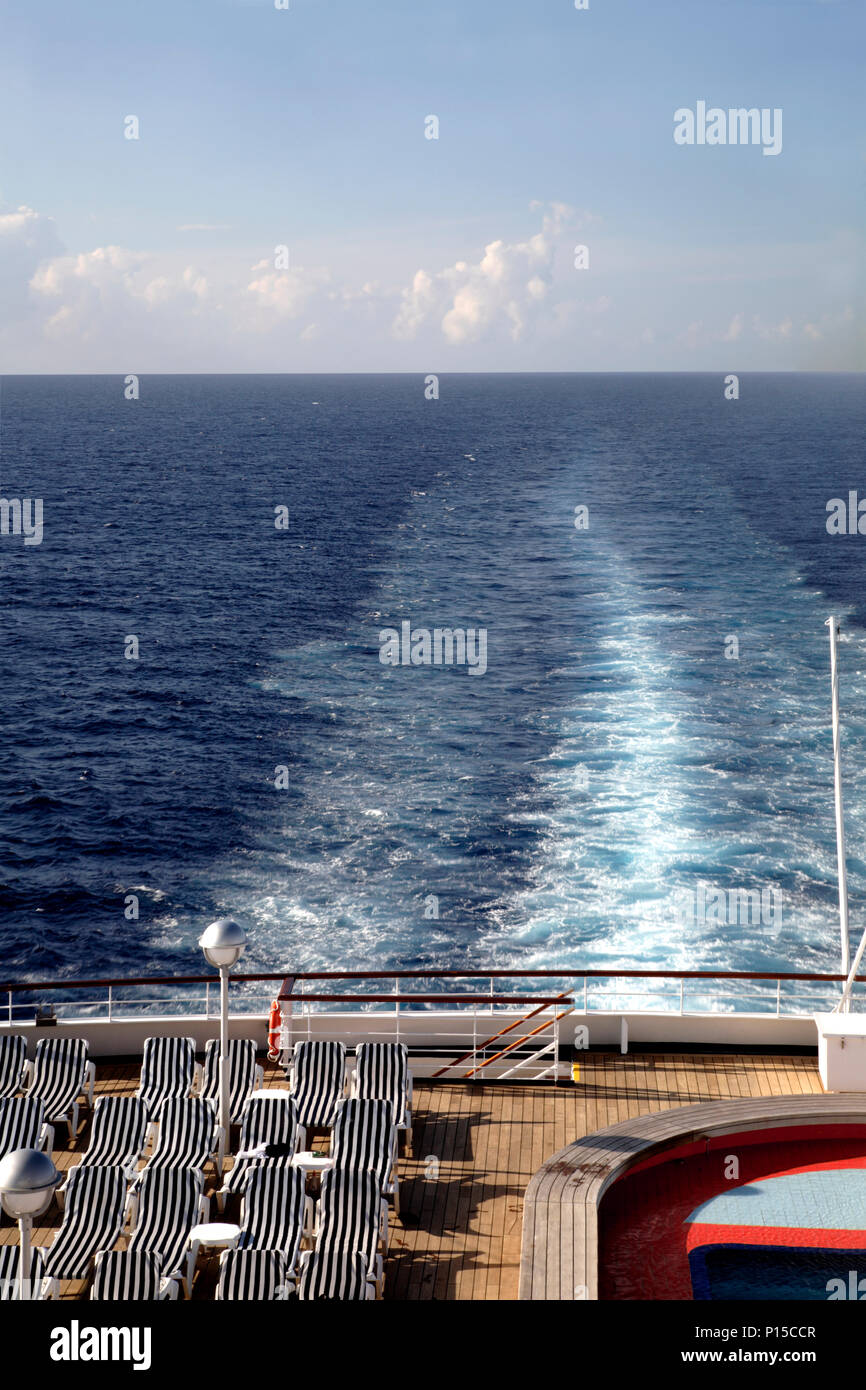 Deck chairs line the stern of a Cruise ship in the warm Caribbean sun ...