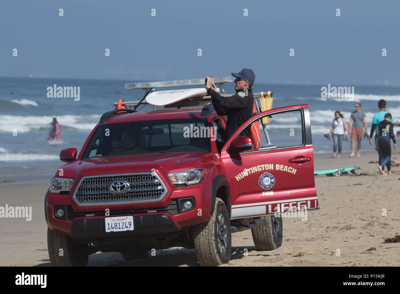 Lifeguard patrolling Huntington Beach California from a lifeguard truck on the beach Stock Photo