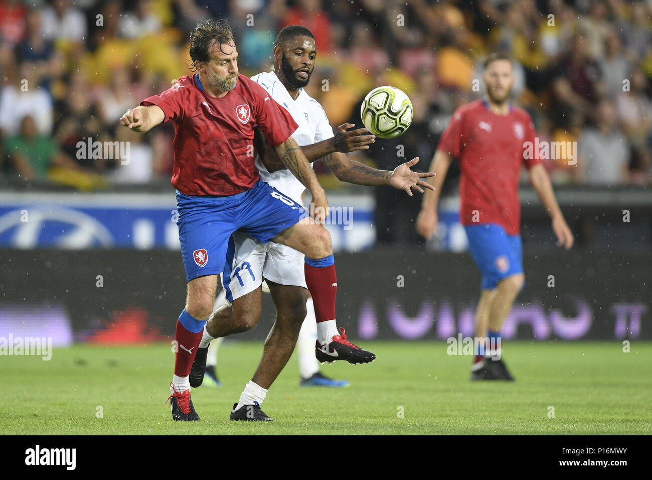 Karel Poborsky of Czech Team, left, and Alex Song of TR10 World Team in action during the match. Former captain of the Czech national football team Tomas Rosicky definitely ended his career at the age of 37 in a farewell match played despite a driving cloudburst which postponed its kickoff today, on Saturday, June 9, 2018. The Czech team, in which he played, defeated the 'team of the world,' composed of his former fellow players from Borussia Dortmund and Arsenal London, 5-2. The final goal was scored by Rosicky's four-year-old son Tomas. Weather complicated the farewell match as roughly 20 mi Stock Photo