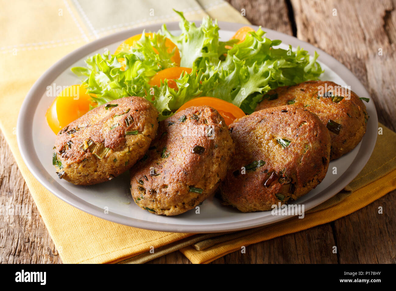Fish cake patties of canned tuna  with fresh vegetable salad close-up on a plate on a table. Horizontal Stock Photo