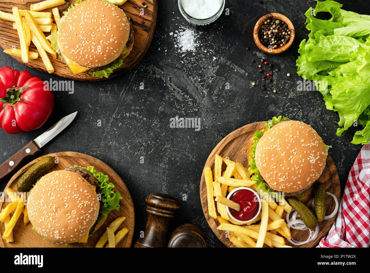 Burgers, hamburgers, french fries and fresh vegetables. BBQ party food. Dark background, top view and copy space for text. Summer barbecue concept Stock Photo
