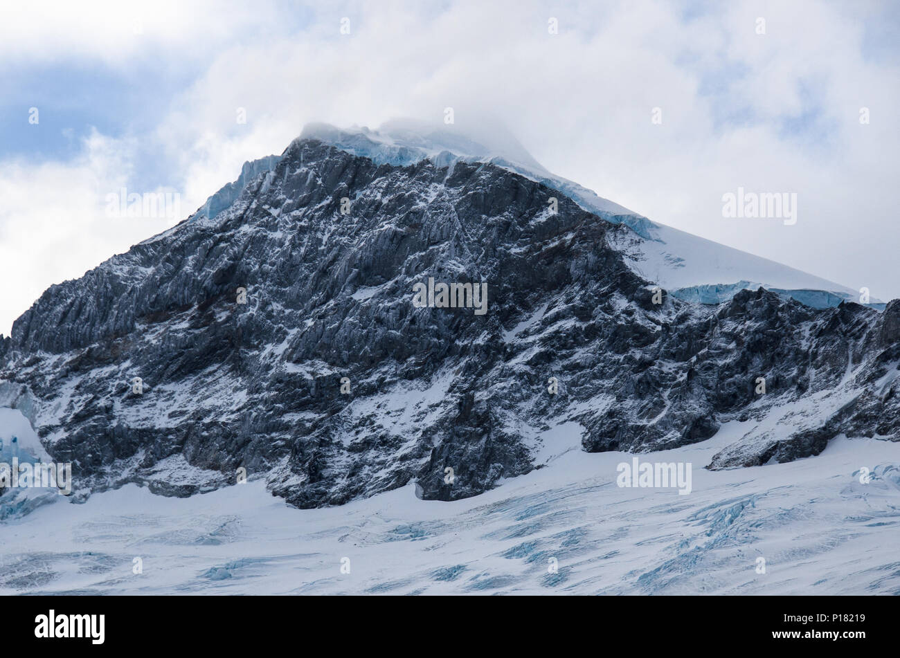 Snowy mountain peak, closeup. Roughed snow topped summit peak with rocky cliff face. Andes mountains, Chile. Stock Photo