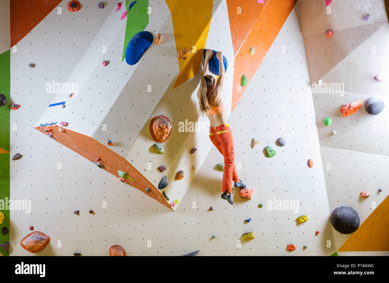 Young woman climbing bouldering route. In indoor climbing gym Stock