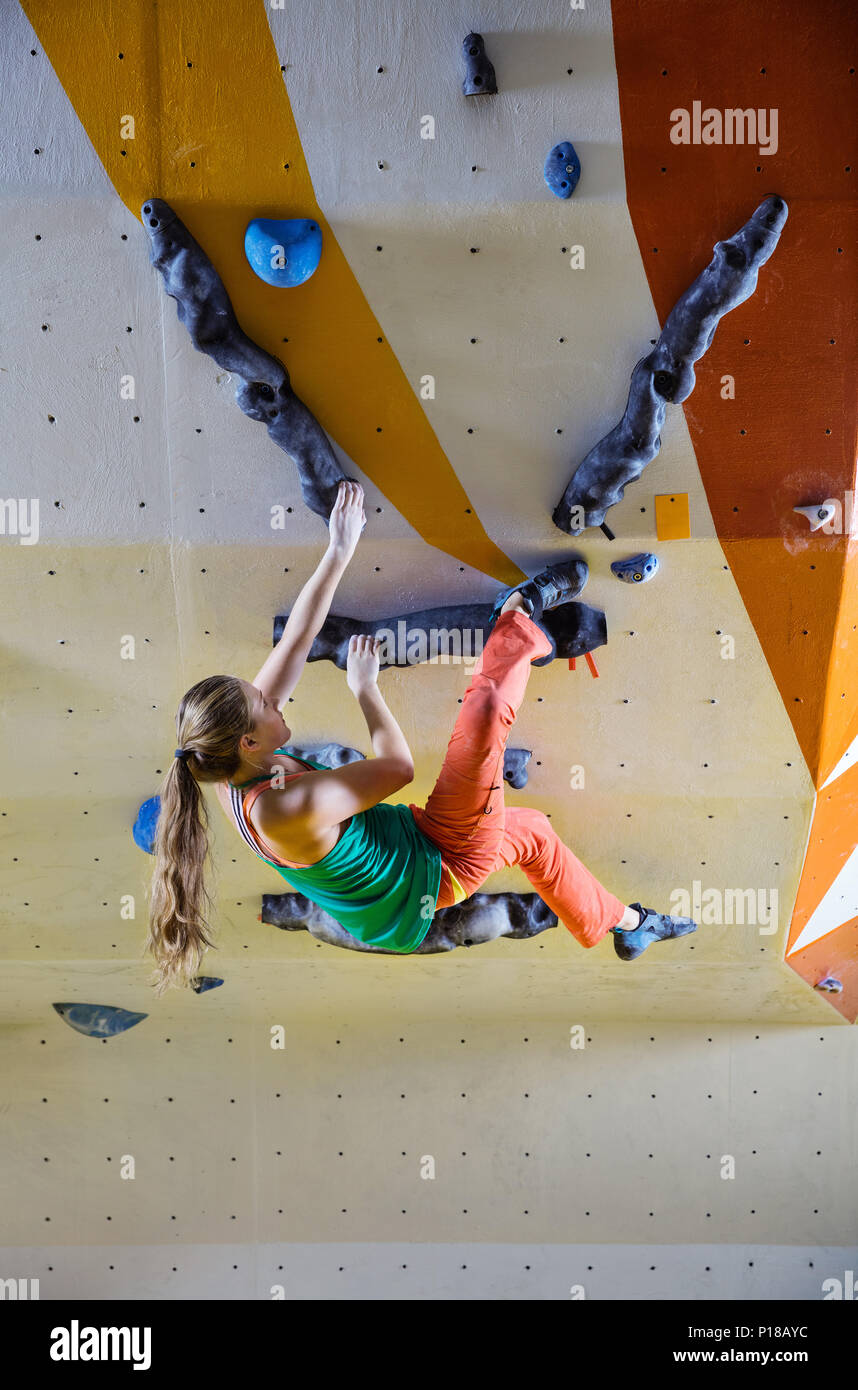 Young woman climbing bouldering route. In indoor climbing gym Stock