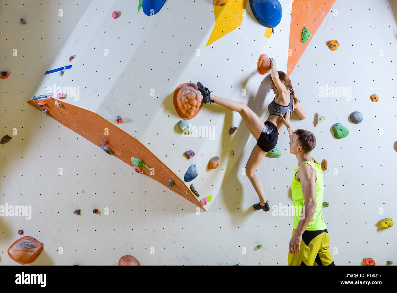 Rock climbers in climbing gym. Young woman climbing bouldering problem
