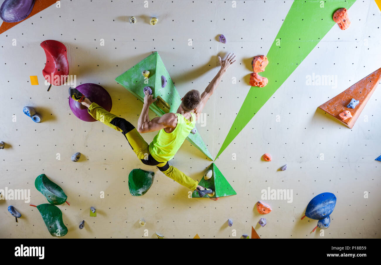 Young man climbing bouldering route, doing splits to reach next handhold.  In indoor climbing gym Stock Photo - Alamy