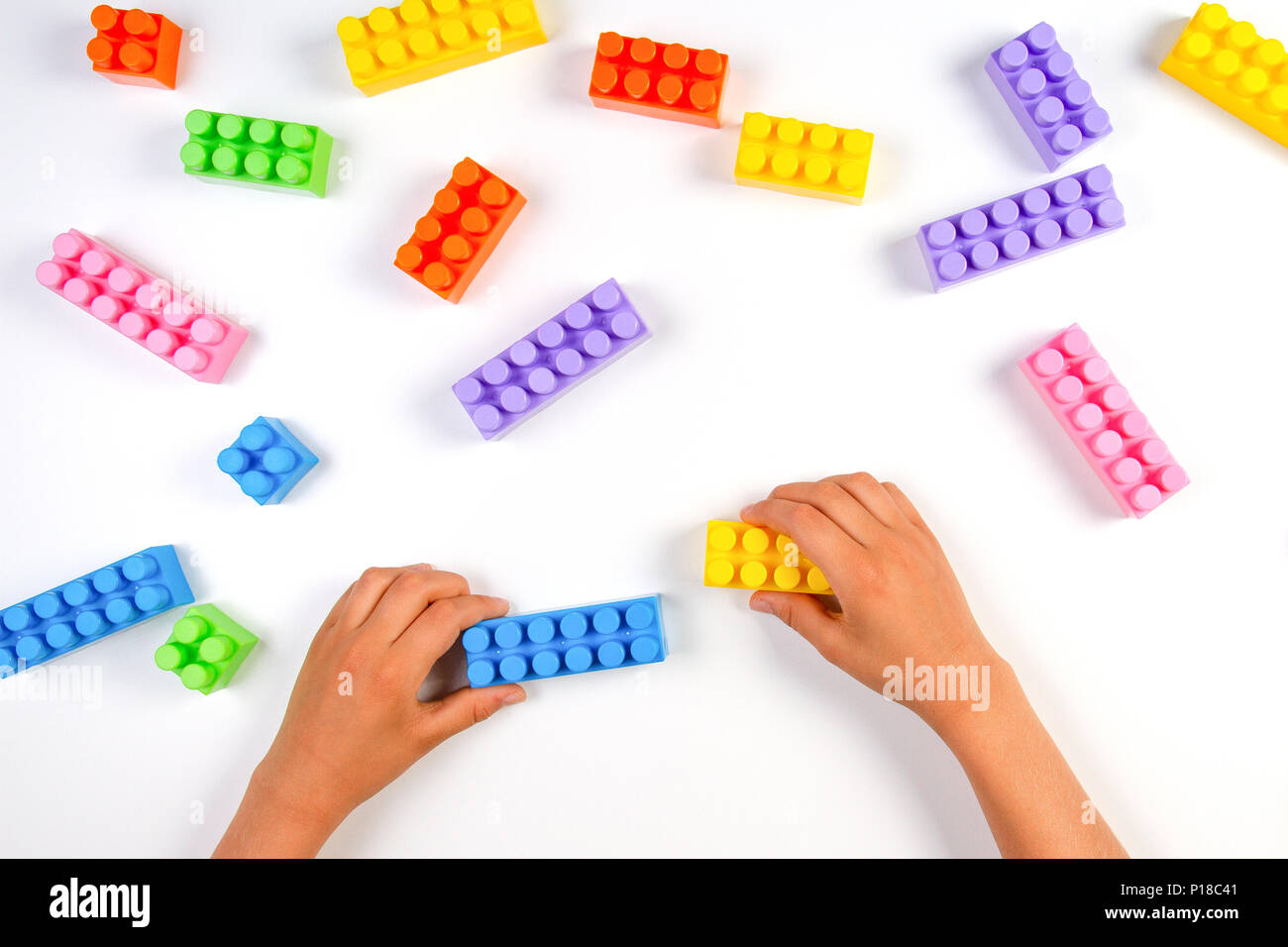 Kid hands play with colorful plastic construction blocks on white ...
