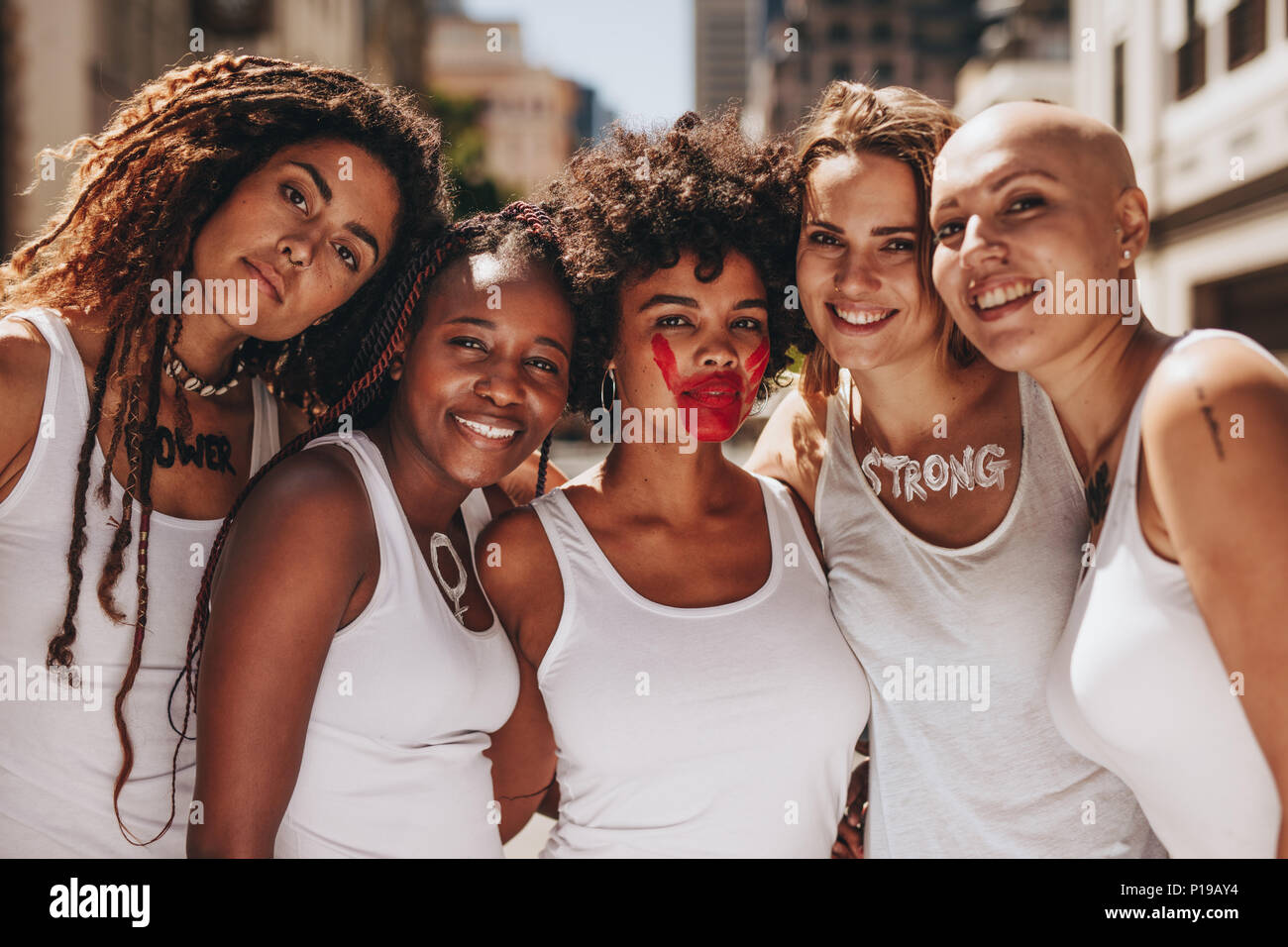 Group of women in dress code protesting outdoors. Smiling females protesting for women rights. Stock Photo