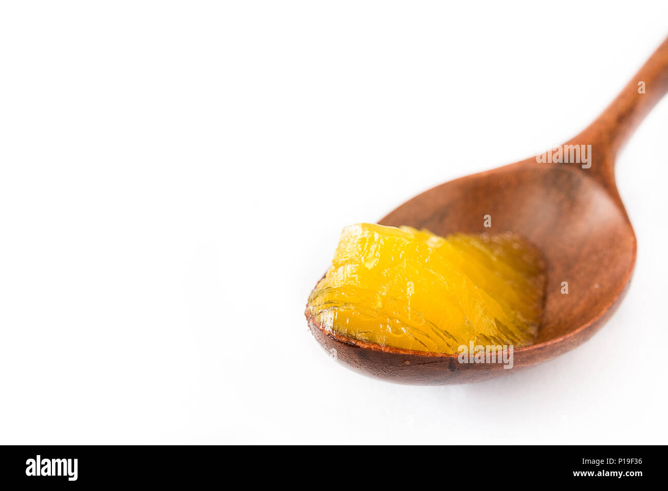 Ghee or clarified butter in wooden spoon isolated on white background
