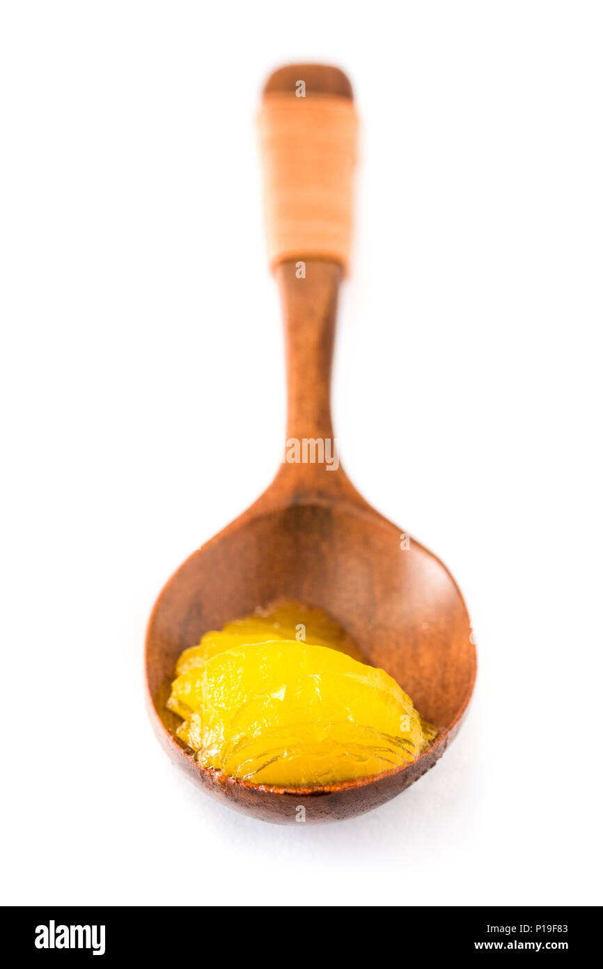 Ghee or clarified butter in wooden spoon isolated on white background