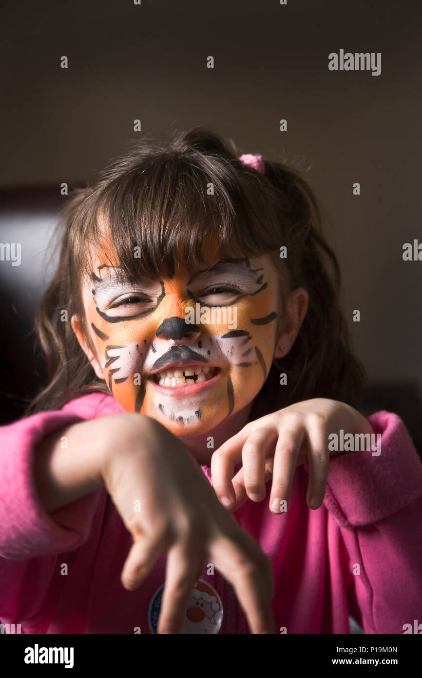 Little girl with tiger face painting imitating tiger growl to camera Stock Photo