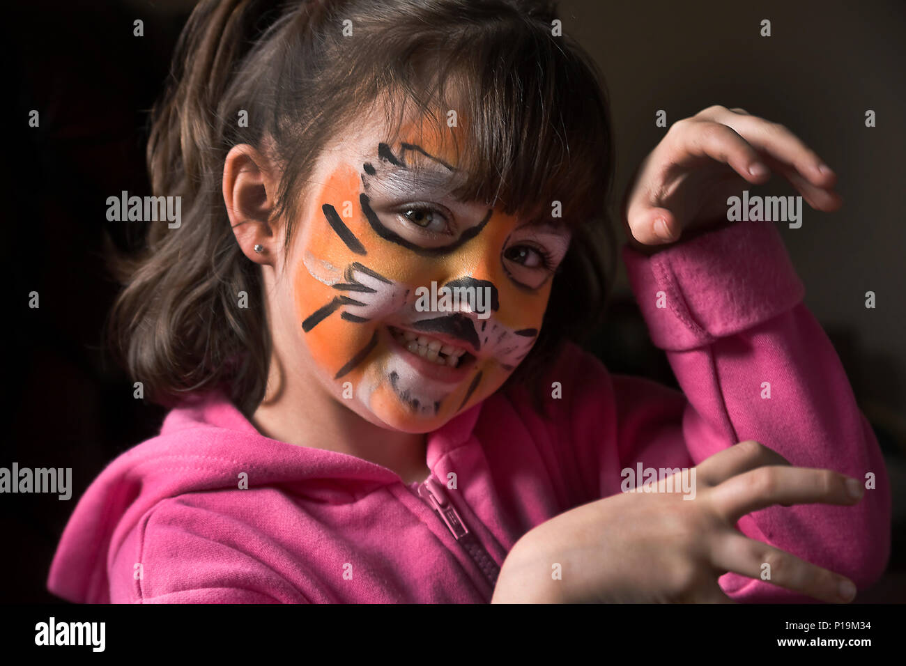 Little girl with tiger face painting imitating tiger growl to camera Stock Photo