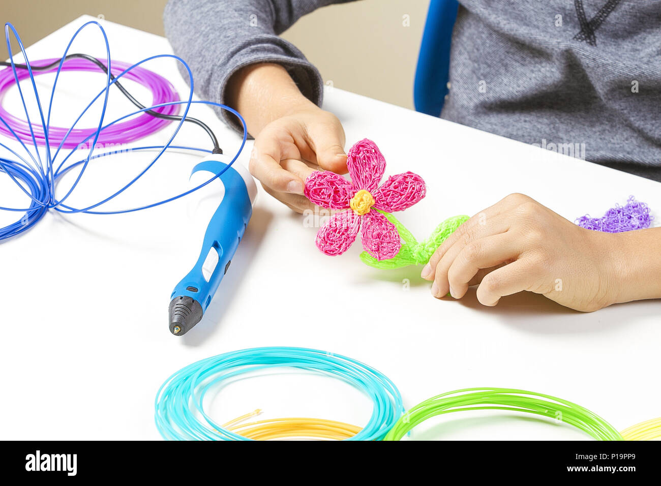Kid hands creating with 3d pen, colorful filaments on white desk Stock  Photo - Alamy