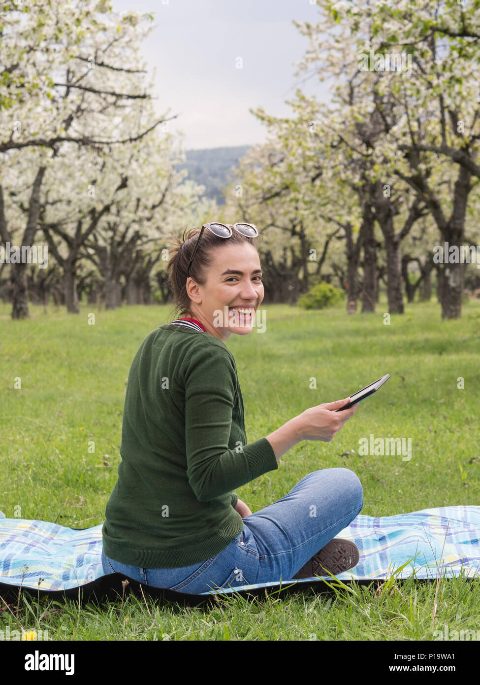 Young attractive woman holding a tablet outdoors and laughing Stock Photo