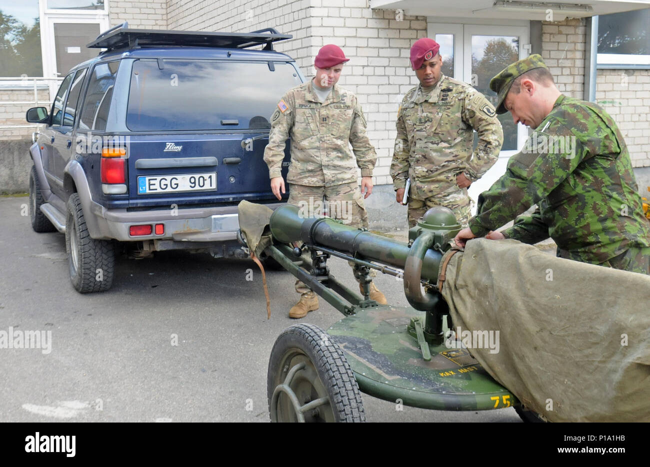 SIAULIAI, Lithuania – A Lithuanian Soldier assigned to the 6th Territorial Unit of Prisikelimo Military District National Guard, shows U.S. Army Capt. Anthony Formica and 1st Sgt., Roberto Ayala a Swedish made Pansarvärnspjäs 1110 90mm recoilless rifle Oct. 1 during a visit to a “safe house” the National Guard was using to practice reconnaissance missions.  Formica and Ayala, the commander and first sergeant of Able Company, 2nd Battalion, 503rd Infantry Regiment, 173rd Airborne Brigade, visited the Lithuanian National Guard to discuss joint training opportunities between the two units. The Li Stock Photo