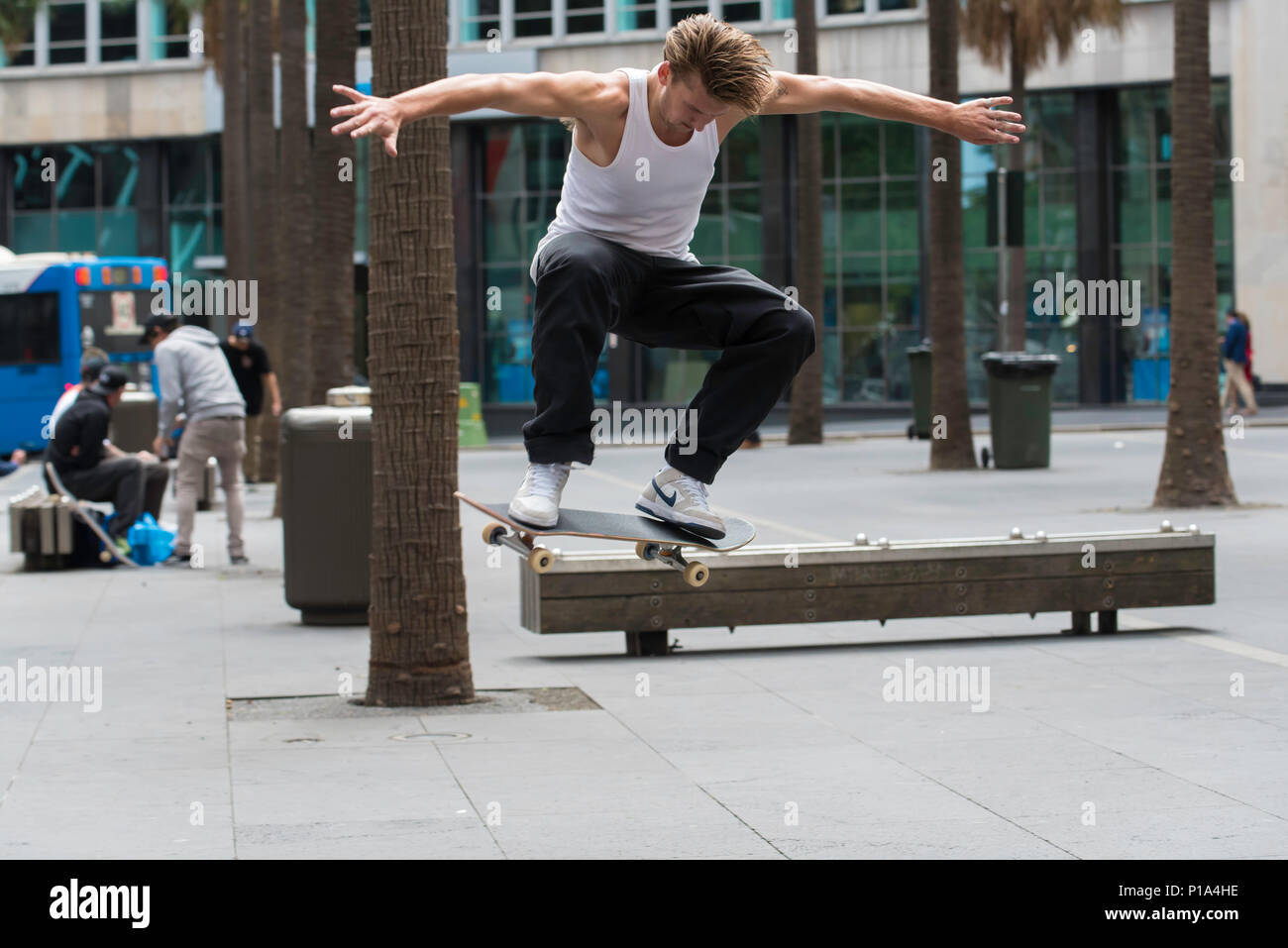 A skateboard rider performs a trick over a bench in Sydney city