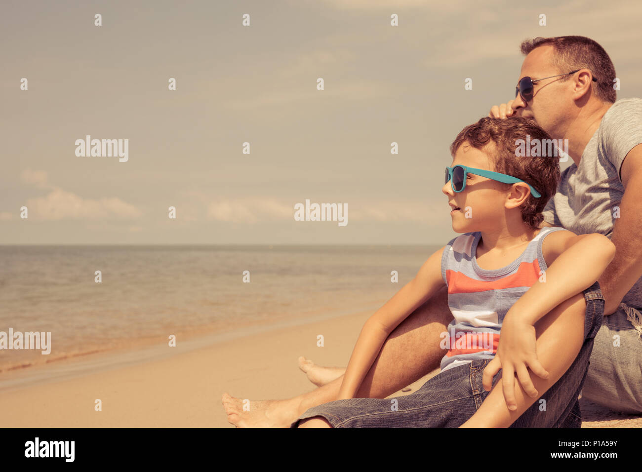 Father and  son playing on the beach at the summer day time. People having fun outdoors. Concept of summer vacation and friendly family. Stock Photo