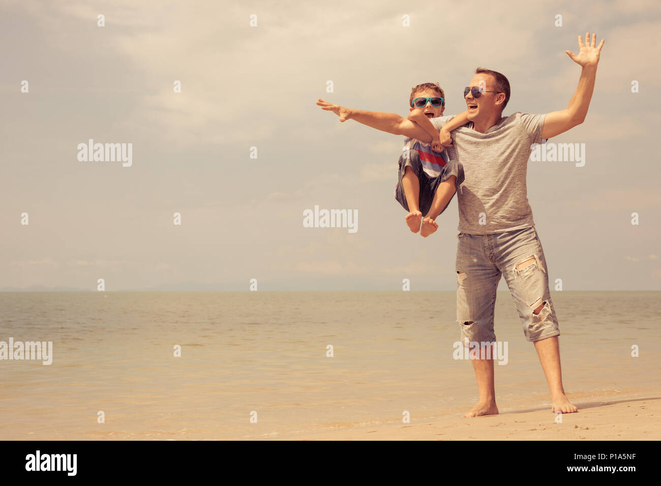 Father and  son playing on the beach at the summer day time. People having fun outdoors. Concept of summer vacation and friendly family. Stock Photo