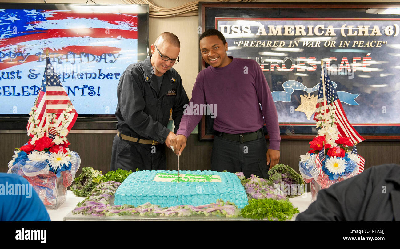 161005-N-VR008-113 PACIFIC OCEAN (Oct. 5, 2016) Master Chief Petty Officer  Kenneth Robertson, command master chief on board amphibious assault ship  USS America (LHA 6), and Seaman Armani Reynolds cut the birthday cake