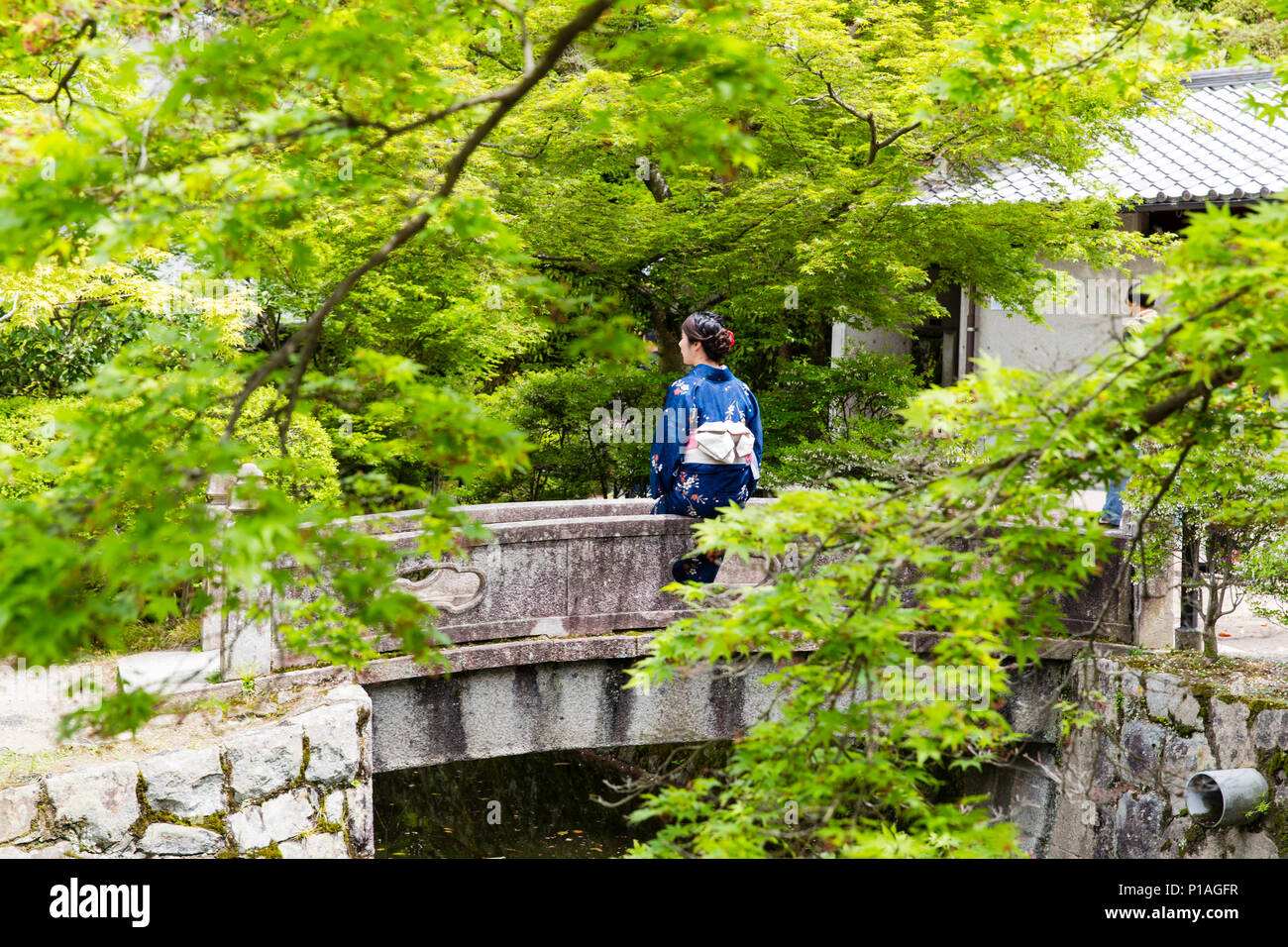 A Woman Dressed as a Geisha Sitting Quietly in the Gardens of Kiyomizu-dera Temple, Kyoto, Japan. Stock Photo