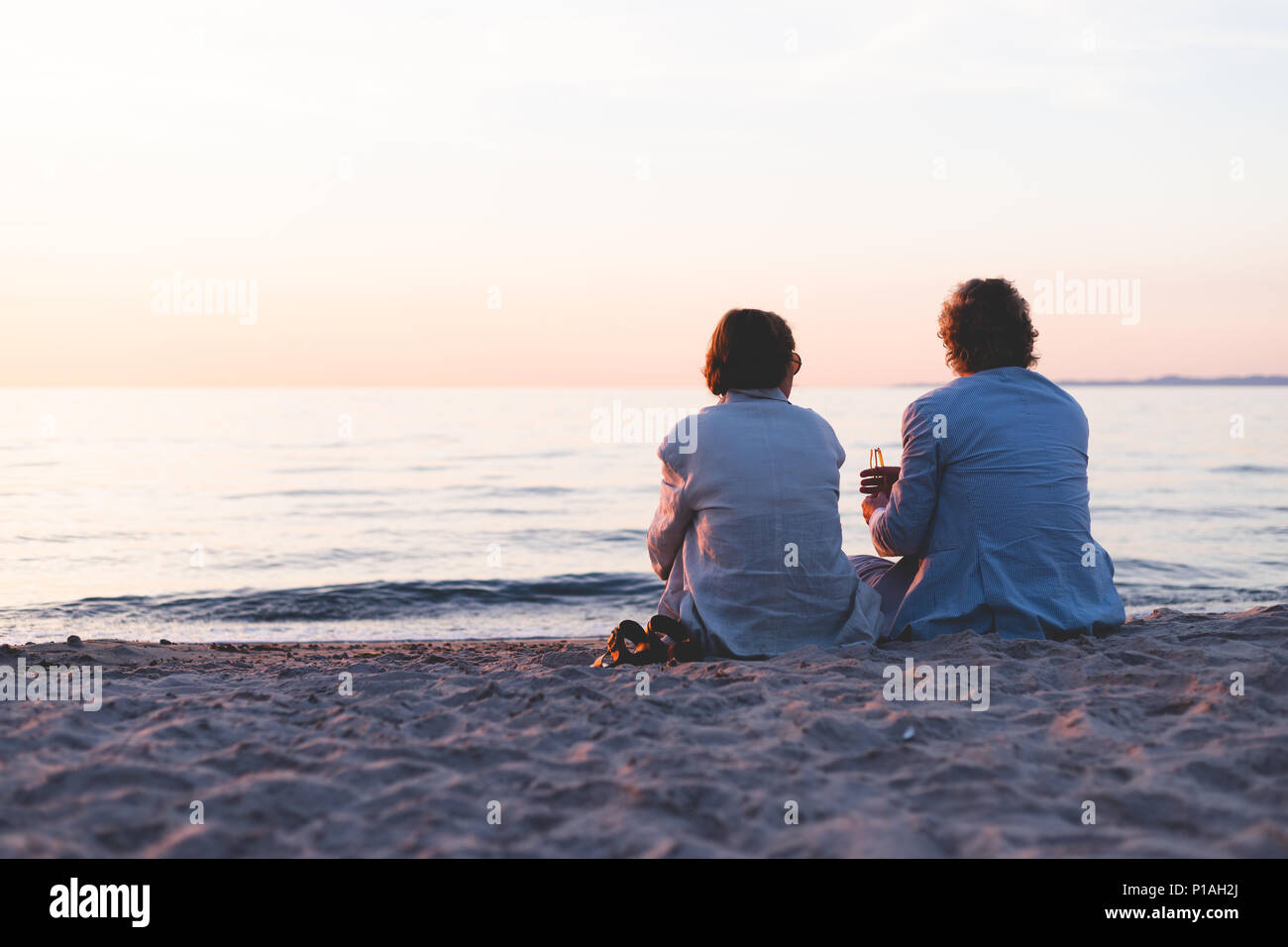 Couple sitting on the beach during sunset, Europe Stock Photo