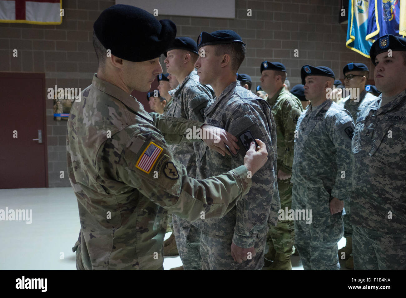 First Lt. James Tollefson, commander of A  Company, 1st Battalion, 297th Infantry Regiment, affixes the 29th Infantry Brigade Combat team patch to mortarman Spc. Drew Gatlin, Oct. 16, 2016, at the Alaska National Guard Armory at Joint Base Elmendorf-Richardson. The 1-297th Infantry activated during the ceremony and became a subordinate unit to 29th IBCT, Hawaii Army National Guard. (U.S. Army National Guard photo by Sgt. David Bedard) Stock Photo