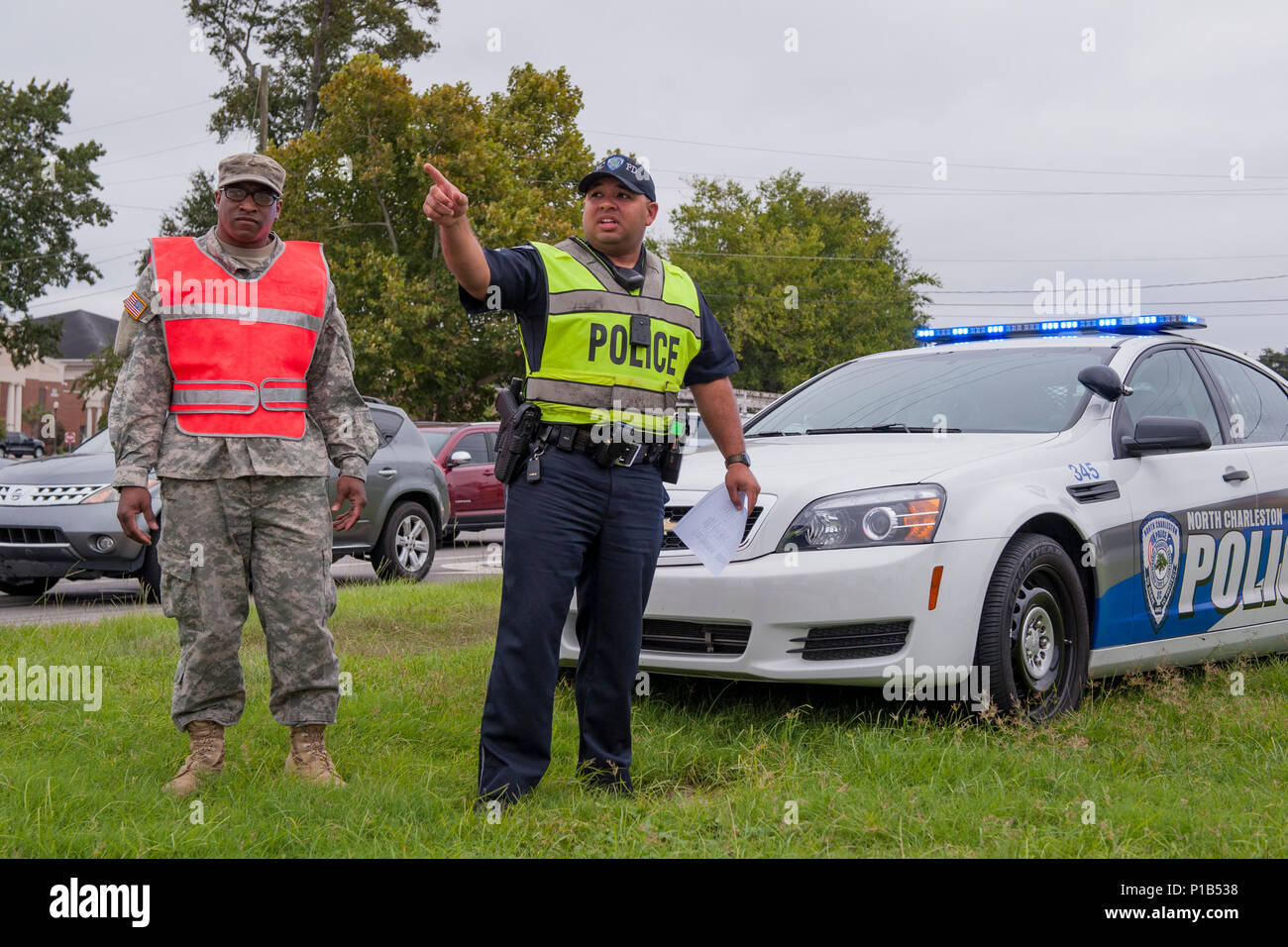 U.S. Army Pvt. 1st Class Bradley Burgess, C Company, 1st Battalion 118th Infantry Regiment, South Carolina Army National Guard, and City of North Charleston Patrolman 1st Class Giovanni Brown manage a traffic control point in North Charleston, South Carolina, Oct. 5, 2016.  Hurricane Matthew peaked as a Category 4 hurricane in the Caribbean and was projected to pass over the southeastern U.S., including the S.C. coast. Approximately 1,400 S.C. National Guard Soldiers and Airmen were activated Oct. 4, 2016, to support coastal evacuations after Governor Nikki Haley declared a State of Emergency. Stock Photo