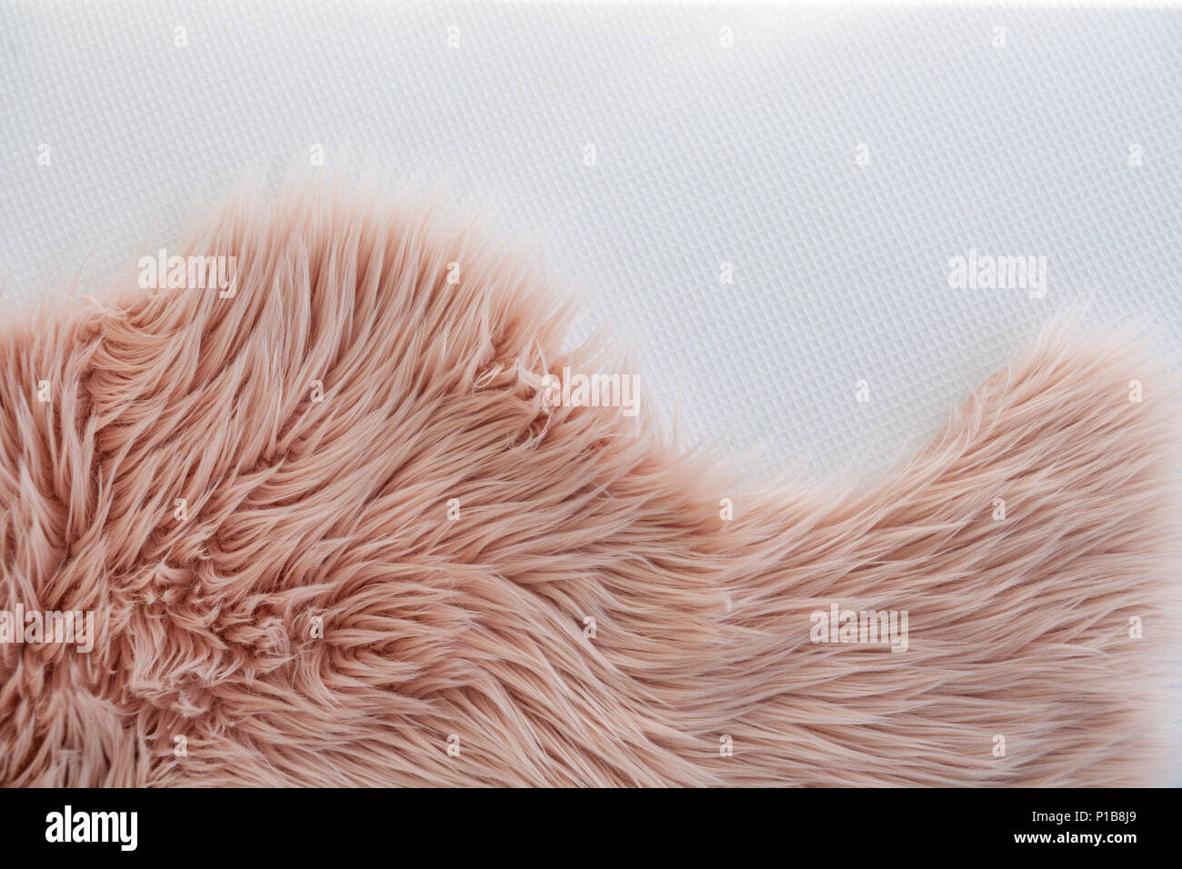 Pink synthetic fluffy fur on white bedding texture background Stock Photo