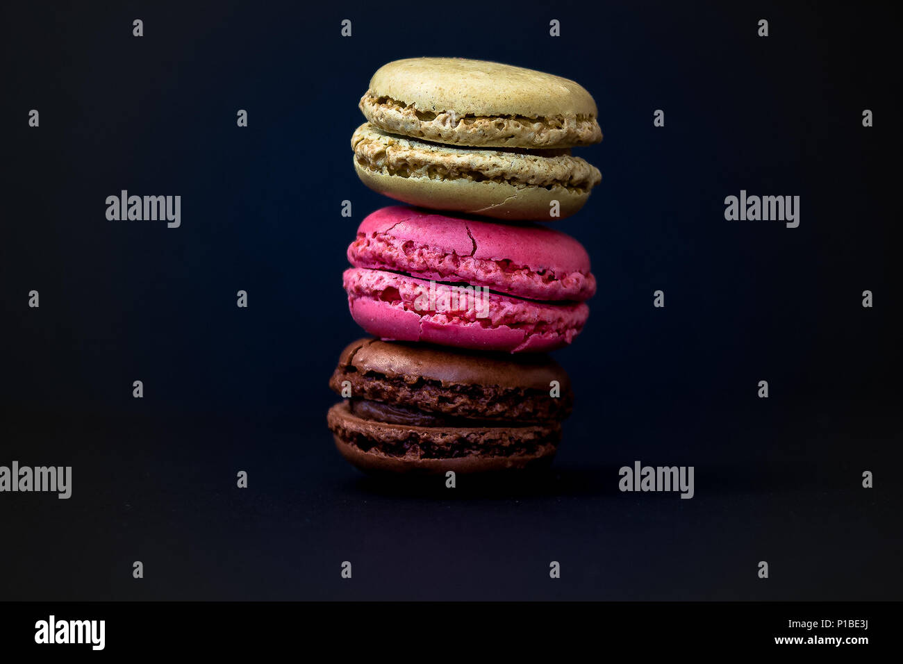 A stack of 3 Macarons, shot against a dark background Stock Photo