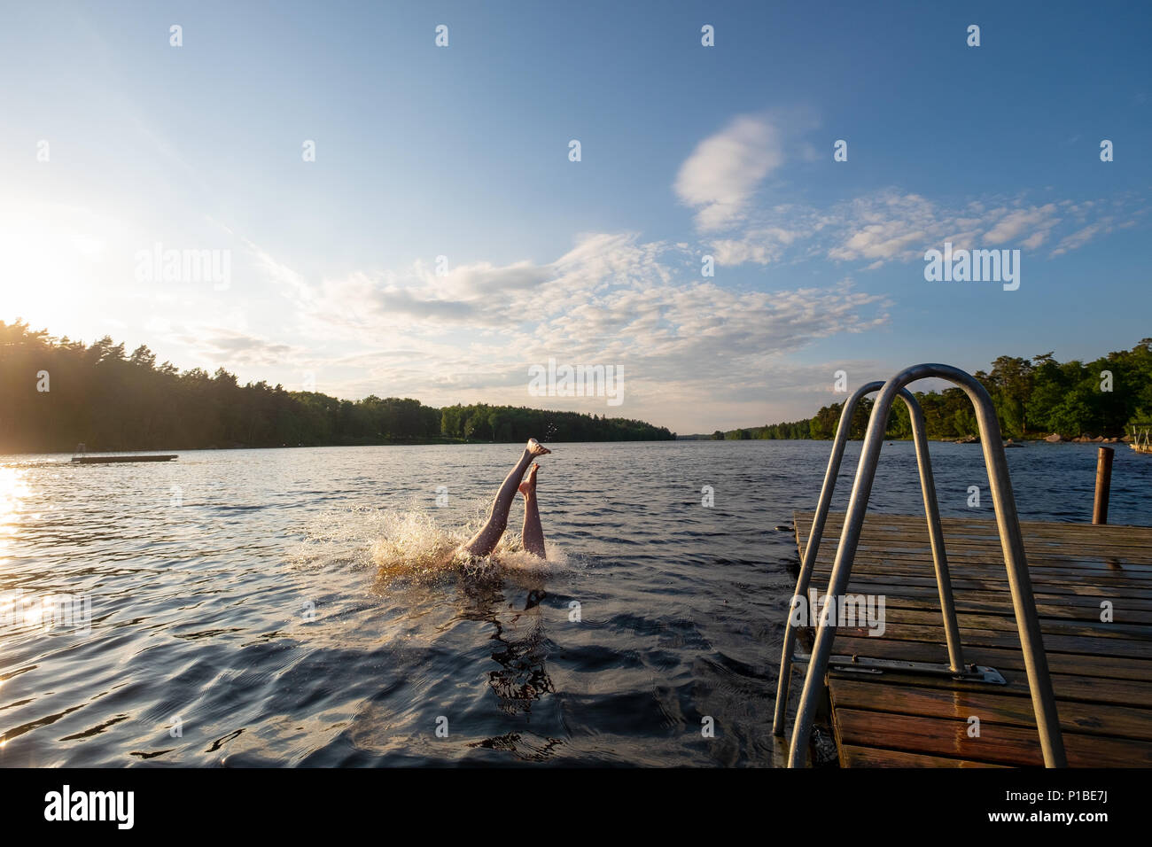 Girl diving into a lake during sunset in the summer, taking a bath