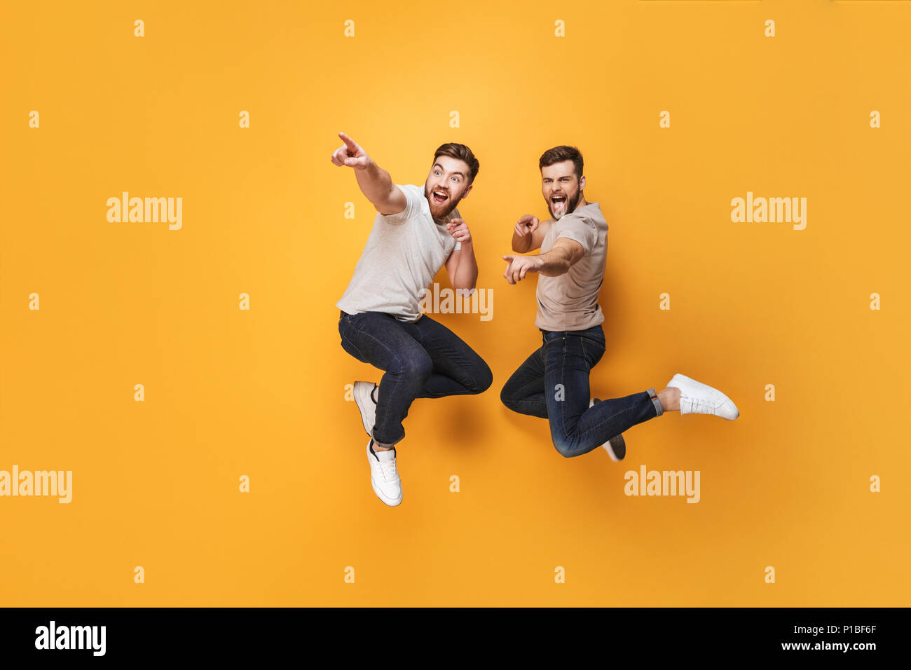 Two Handsome Guys Jumping Two Cheerful Jumping Together And Pointing Away