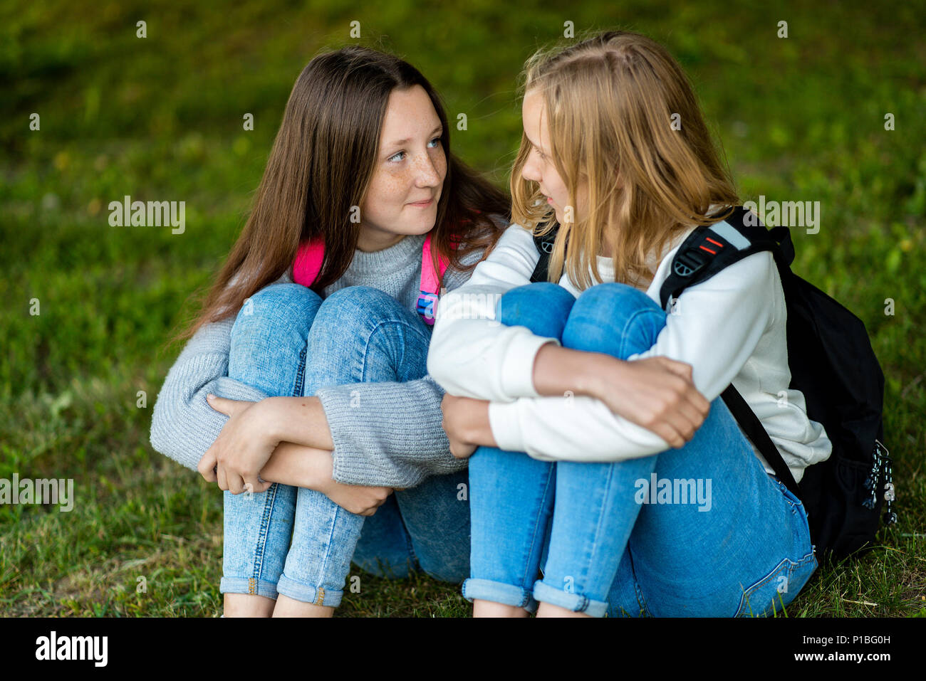 Two teenage girl. Summer in nature. They are sitting on grass