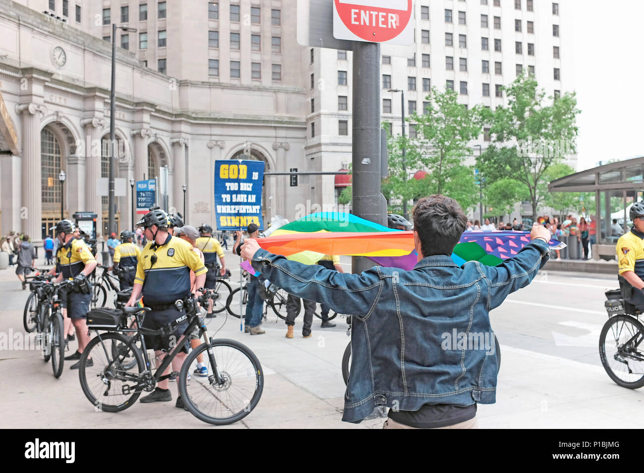 Man waves a rainbow flag in response to the police surrounded religious zealots protesting the Pride celebration in downtown Cleveland, Ohio, USA. Stock Photo