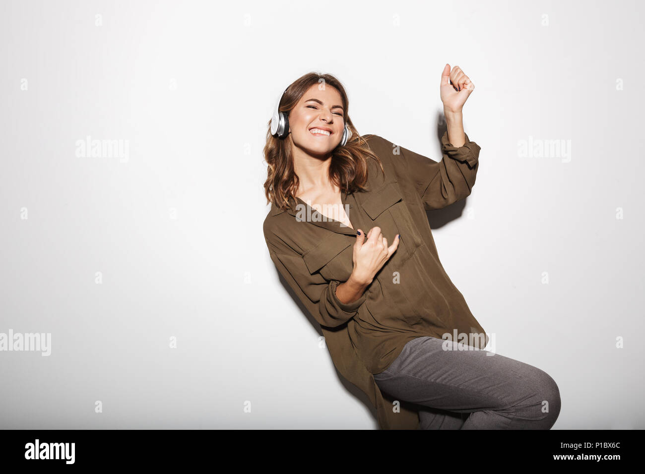 Portrait of a joyful young woman listening to music with headphones and ...