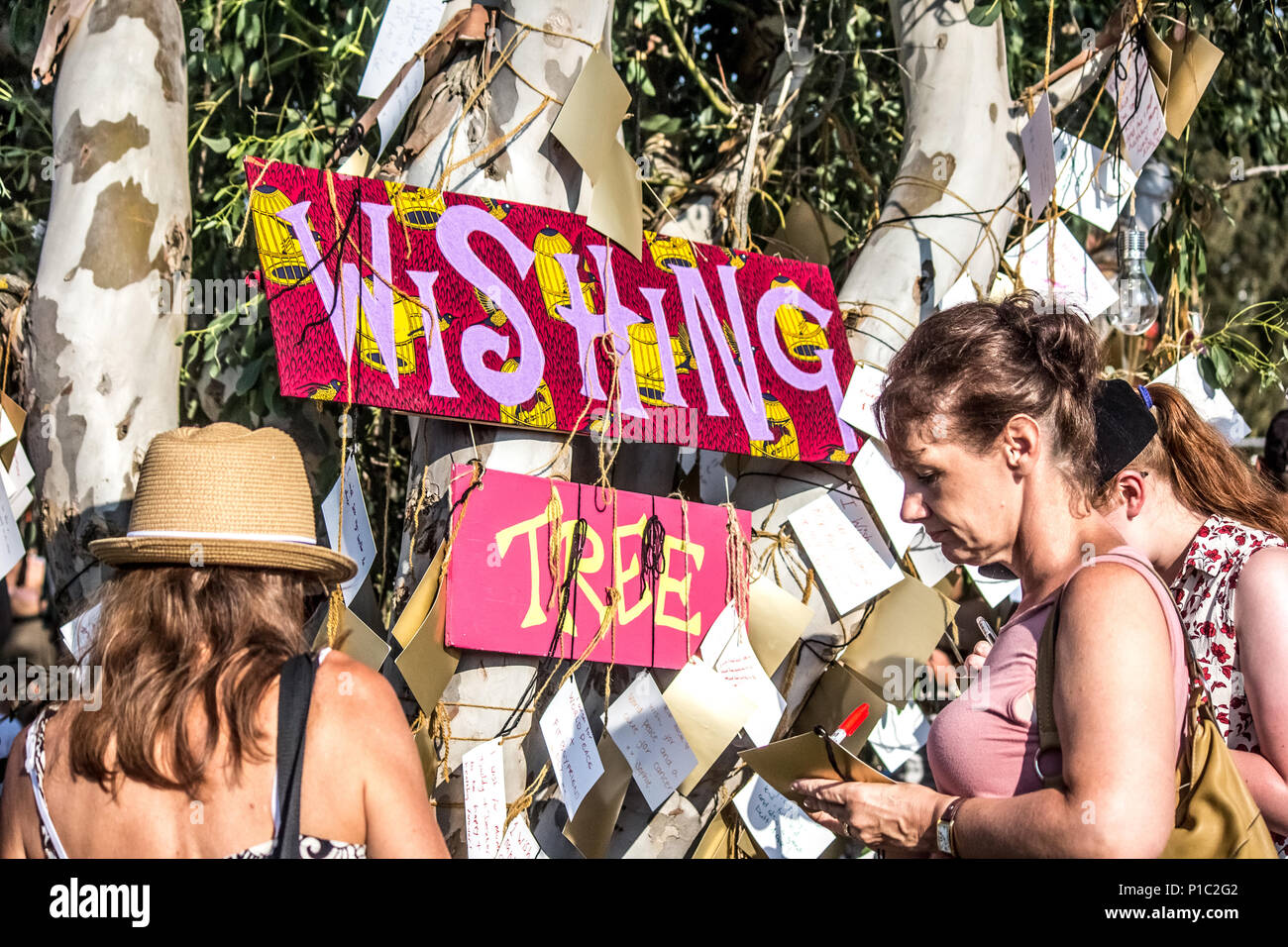 Two women writing wishes at a wishing tree based at a UK festival. Stock Photo