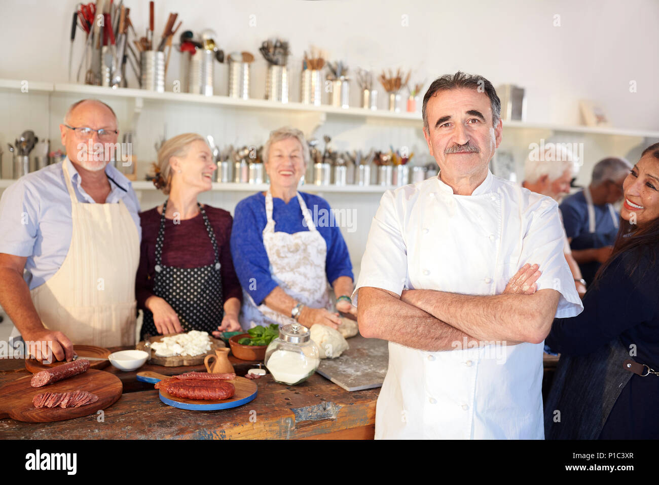 Portrait confident chef with senior students in cooking class kitchen Stock Photo