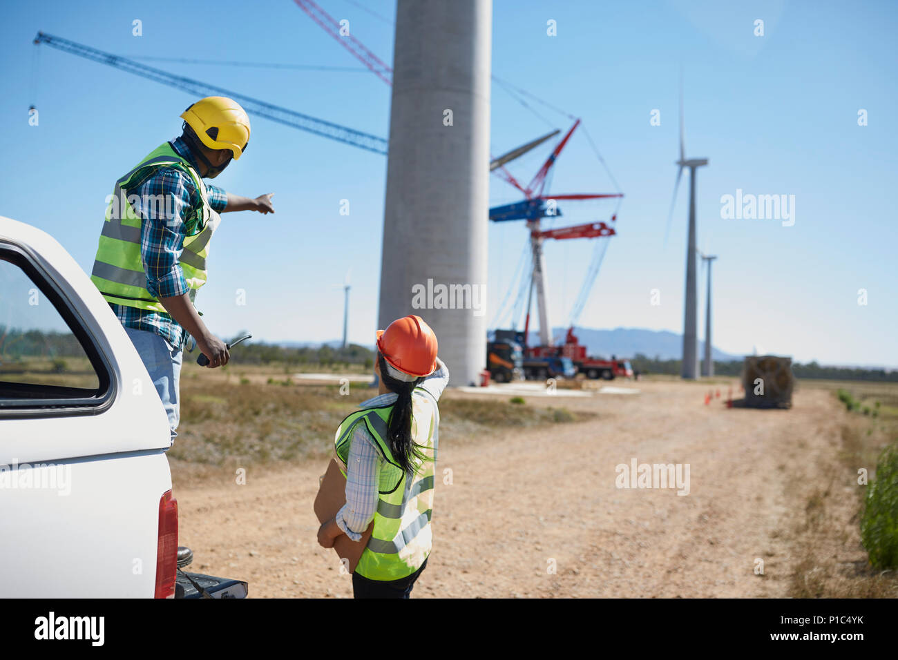 Engineers on dirt road at wind turbine power plant Stock Photo