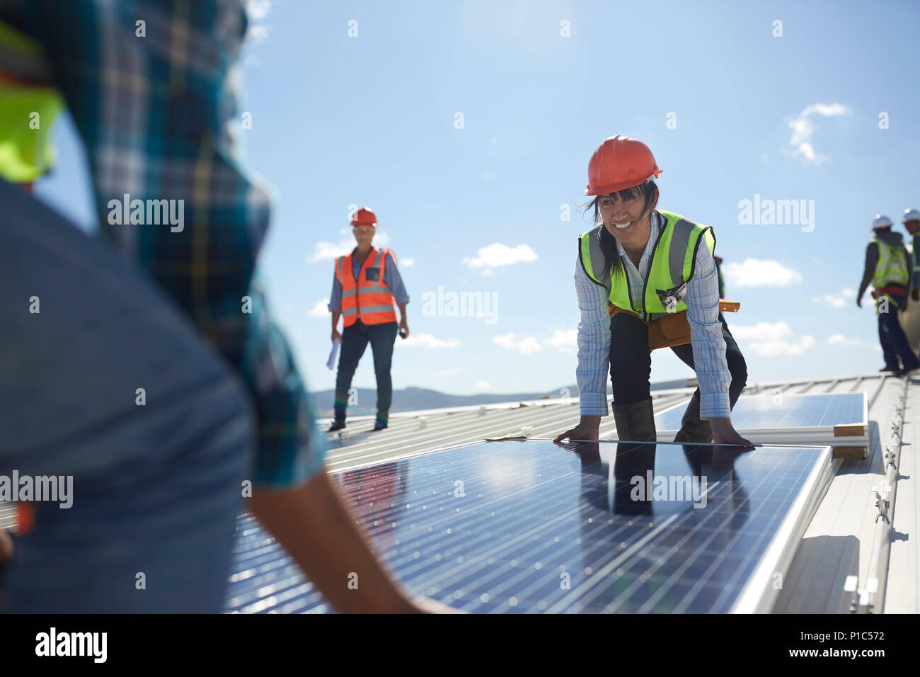 Engineers lifting solar panel at sunny power plant Stock Photo
