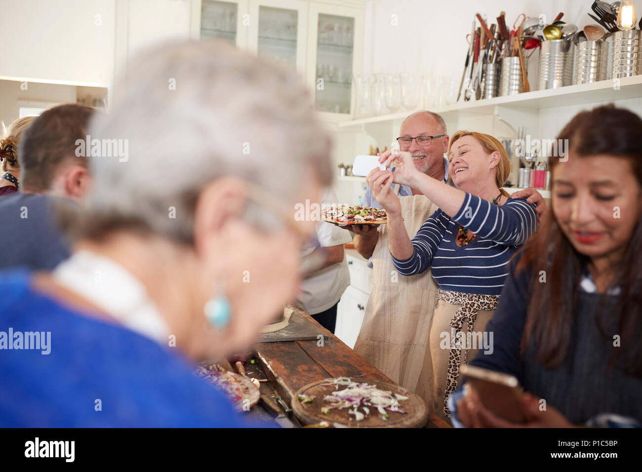 Senior couple taking selfie with pizza in cooking class Stock Photo