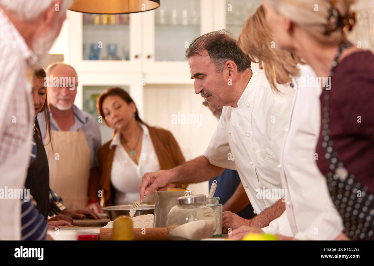 Chef explaining to active senior friends in cooking class Stock Photo