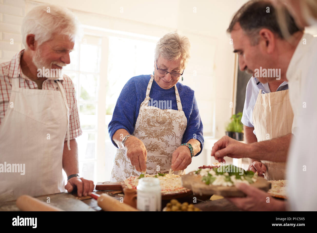 Active senior friends making pizza in cooking class Stock Photo