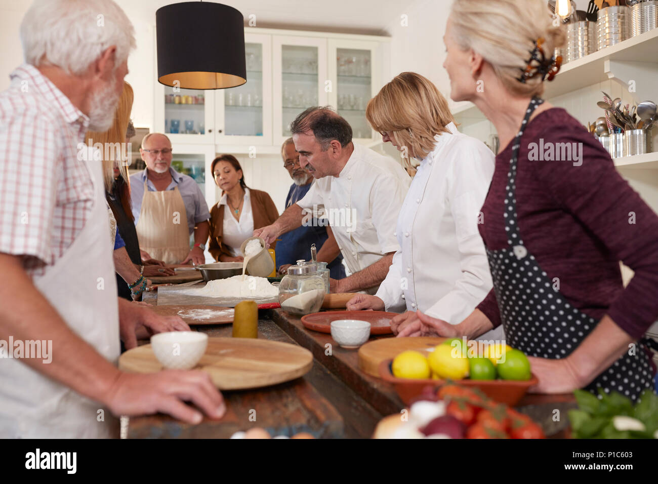 Active senior friends watching chef in pizza cooking class Stock Photo