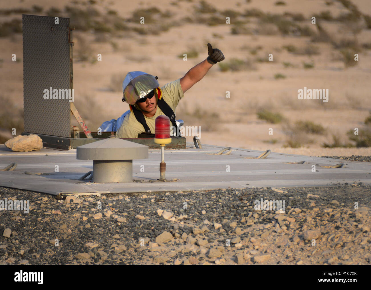 Staff Sgt. Thomas Cabalo, 379th Expeditionary Civil Engineer Squadron firefighter, signals to Airmen inside of the Barrier Arresting Kit-12 to wind up the Aircraft Arresting System Oct. 9, 2016, at Al Udeid Air Base, Qatar. The BAK-12 system works in conjunction with a tensioned cable, known as the pendant, and the BAK-14, a system that raises and lowers the cable as needed. (U.S. Air Force photo/Senior Airman Miles Wilson/Released) Stock Photo