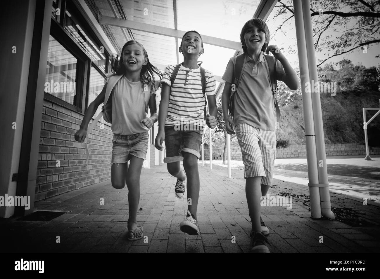 Happy school kids running in corridor Stock Photo