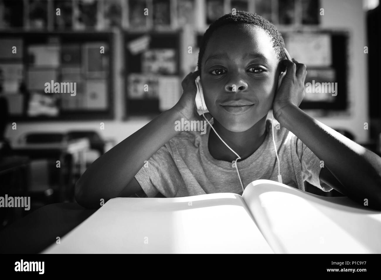 Boy listening music with headphones at desk Stock Photo