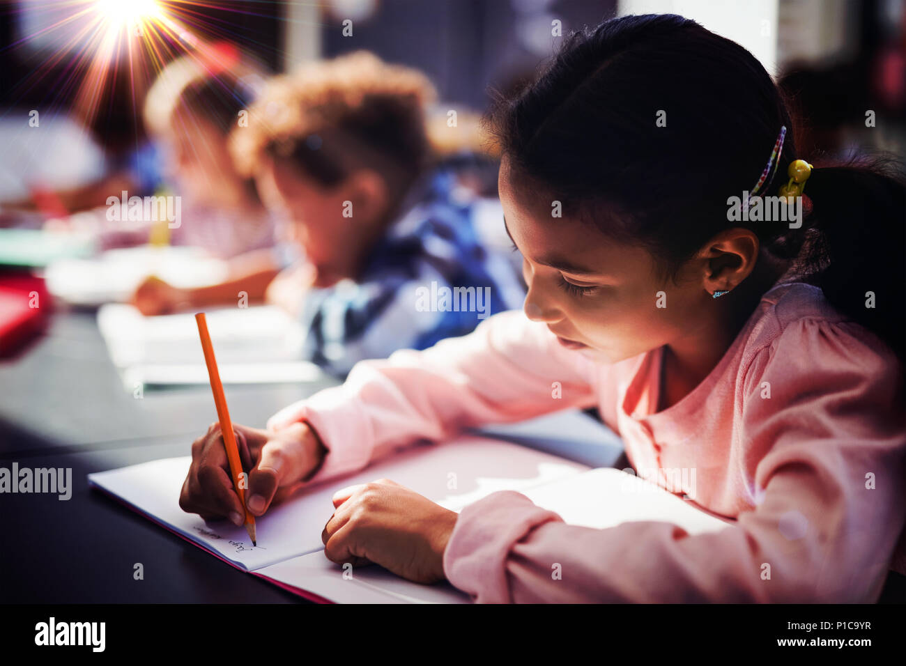 Attentive schoolgirl doing her homework in classroom Stock Photo - Alamy